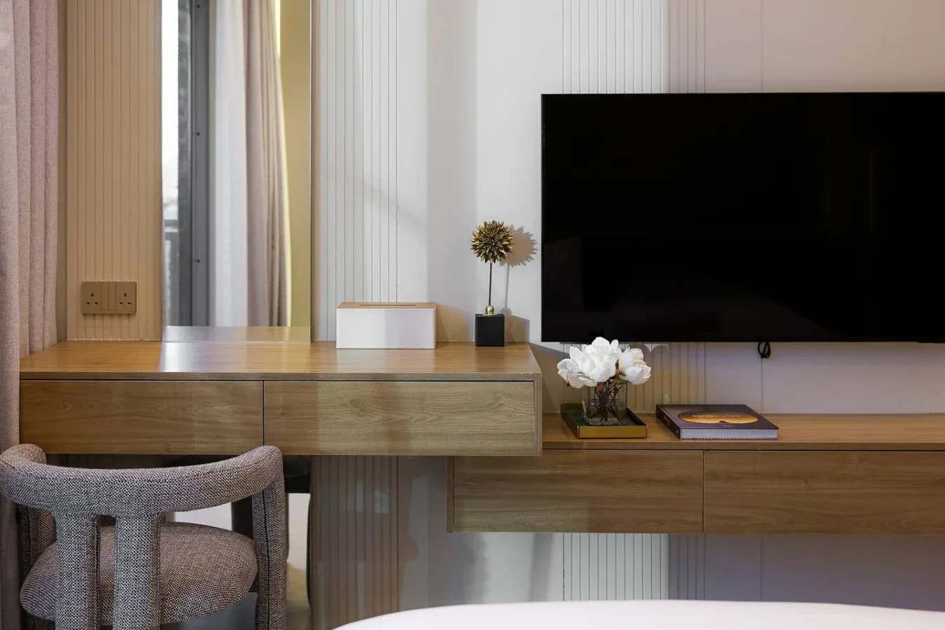 Un escritorio está bajo un televisor montado en la pared, con una silla al lado.