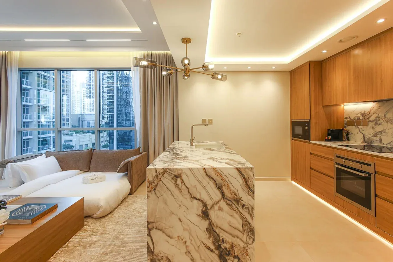 Una cocina y sala de estar modernas y luminosas, con una isla de mármol y grandes ventanas.