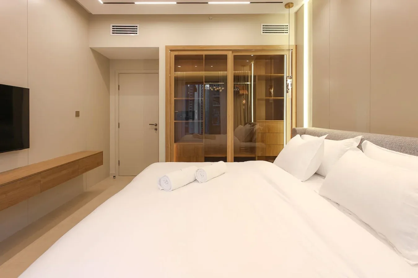 Un dormitorio con una cama grande, un televisor en la pared y armarios de madera.