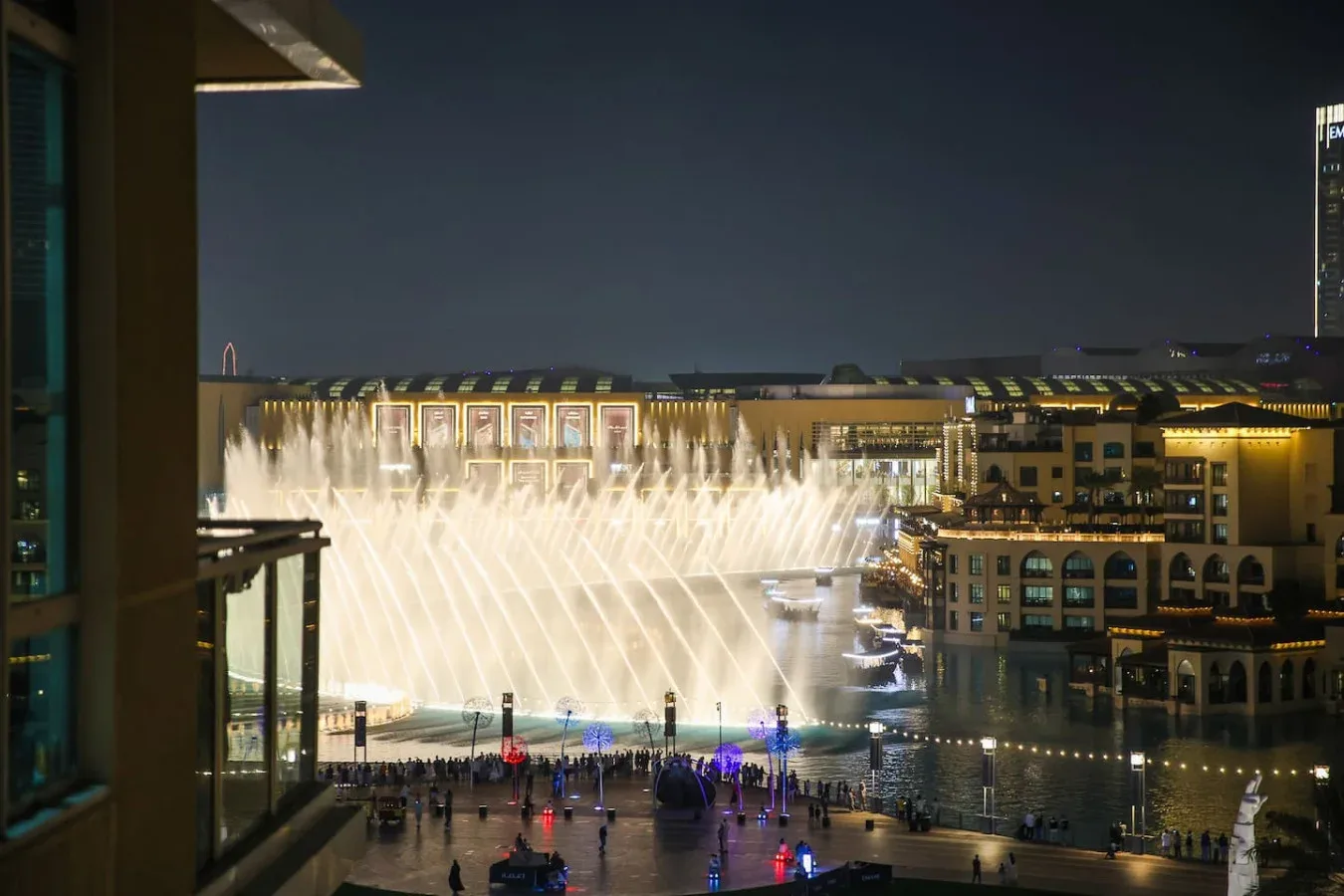Un espectáculo nocturno de fuentes lanza chorros de agua iluminados sobre una gran piscina.