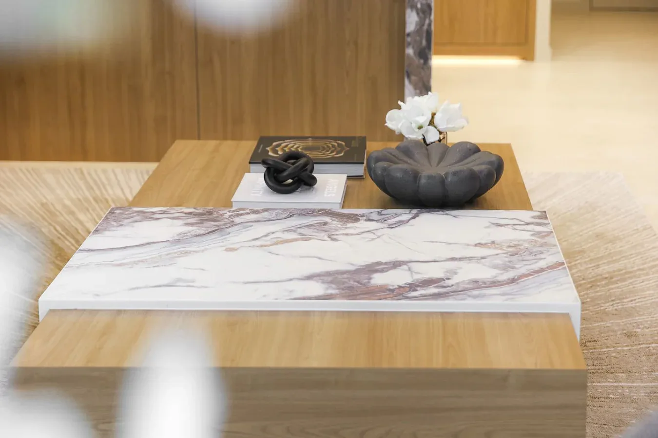 Una mesa de centro en una sala muestra objetos decorativos y un pequeño arreglo floral blanco.