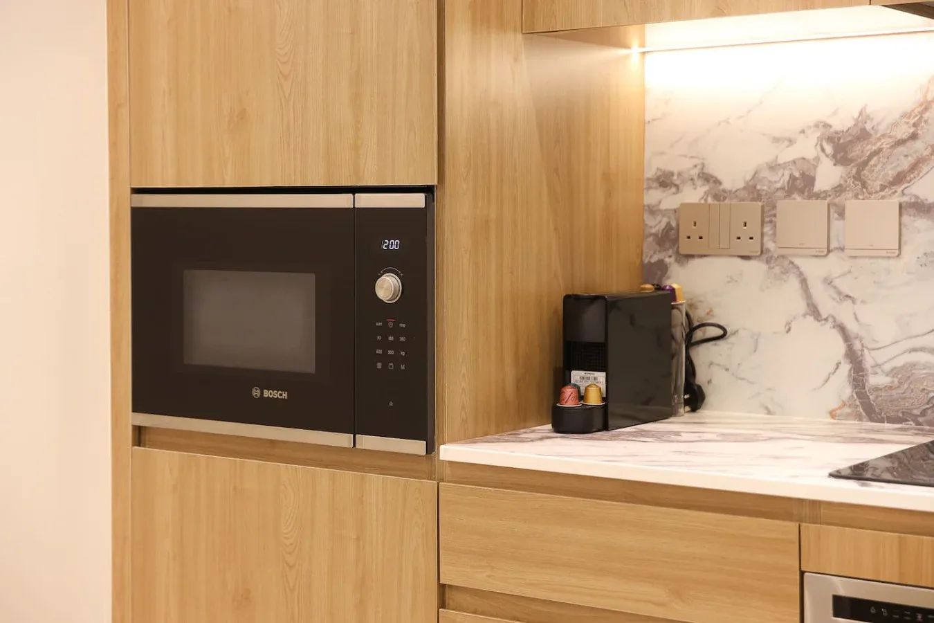 Una encimera de cocina moderna con gabinetes de madera, un microondas y una cafetera.