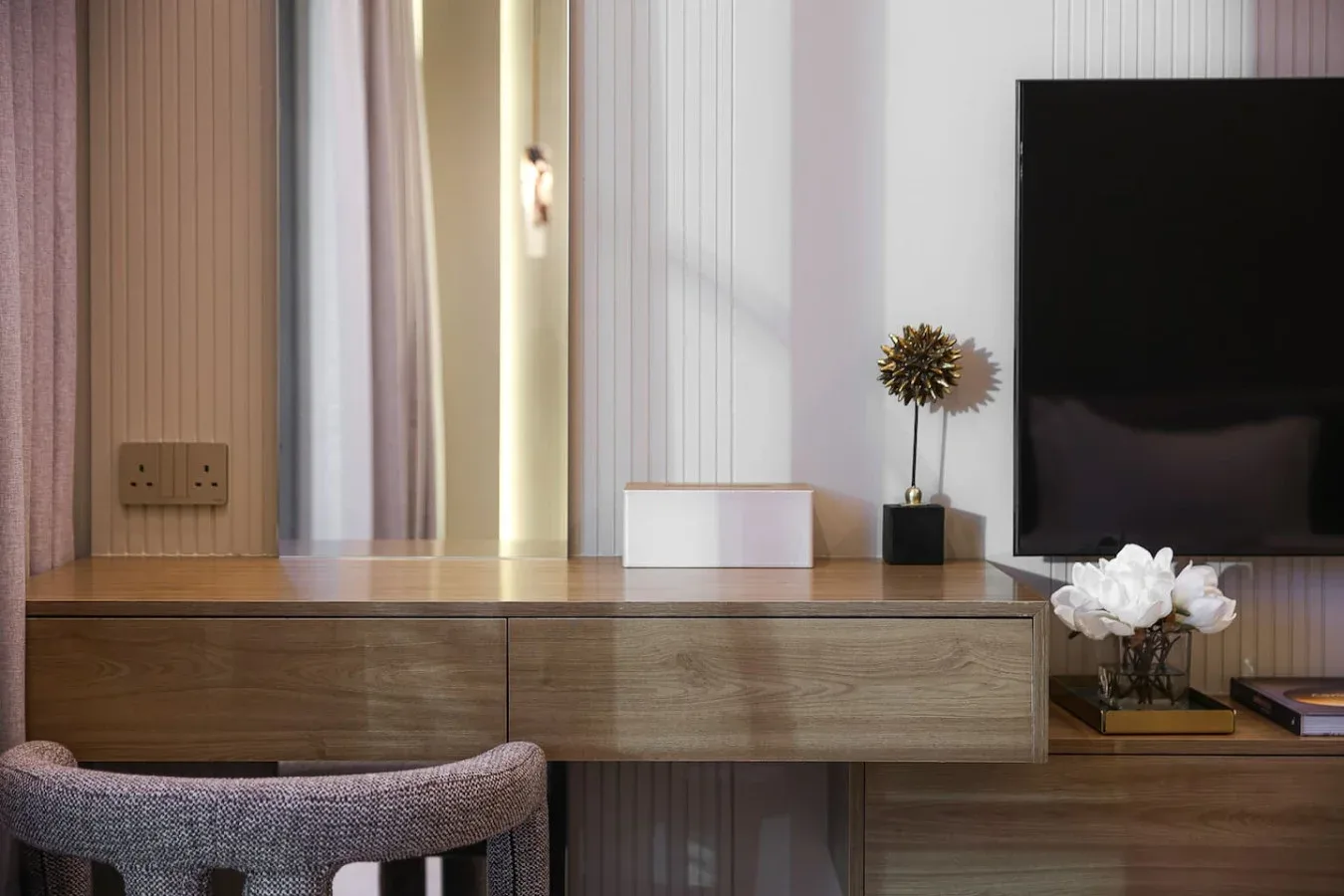 Una zona de tocador en un dormitorio con televisor y flores decorativas.