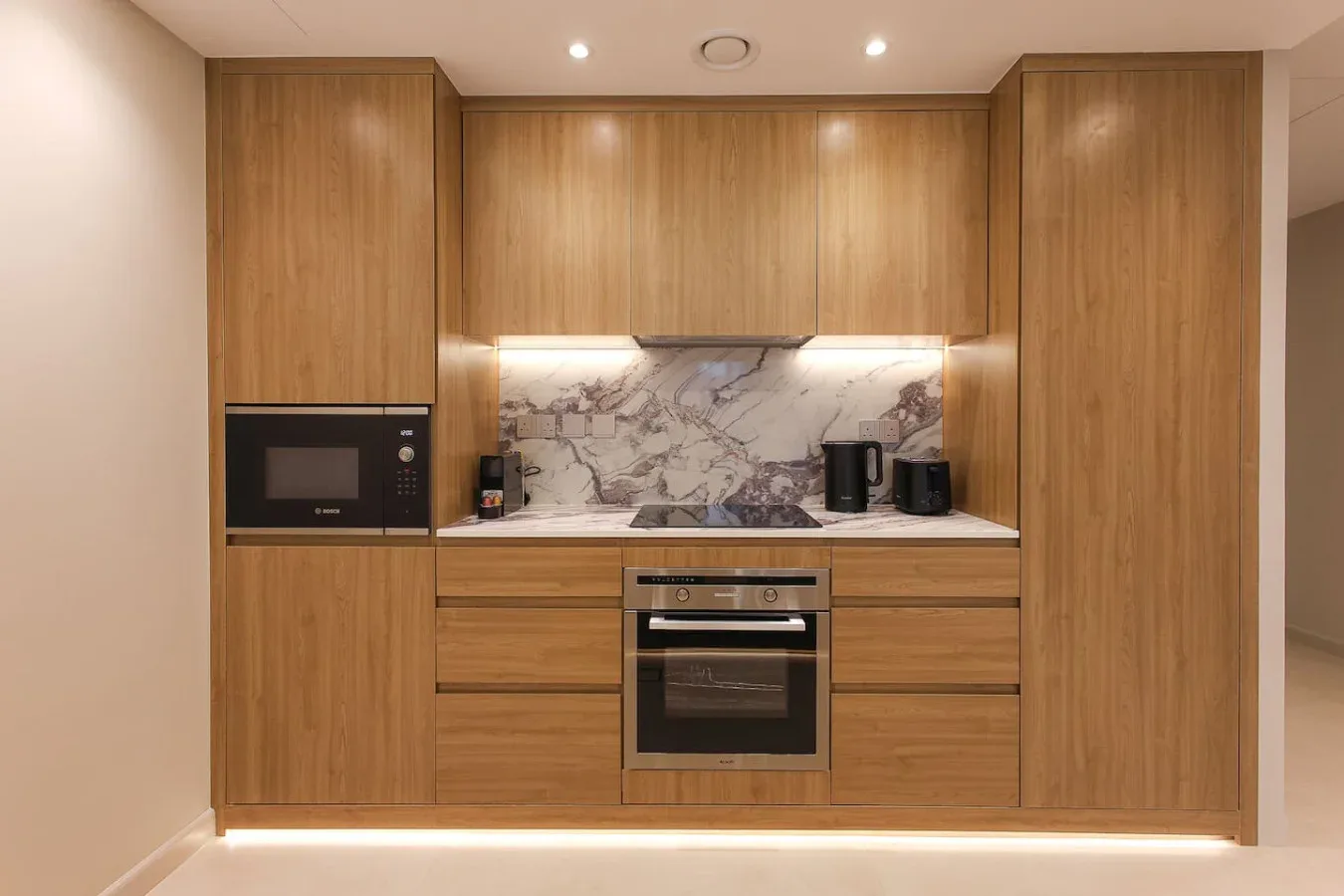 Una cocina moderna con gabinetes de madera, electrodomésticos integrados y un salpicadero veteado.