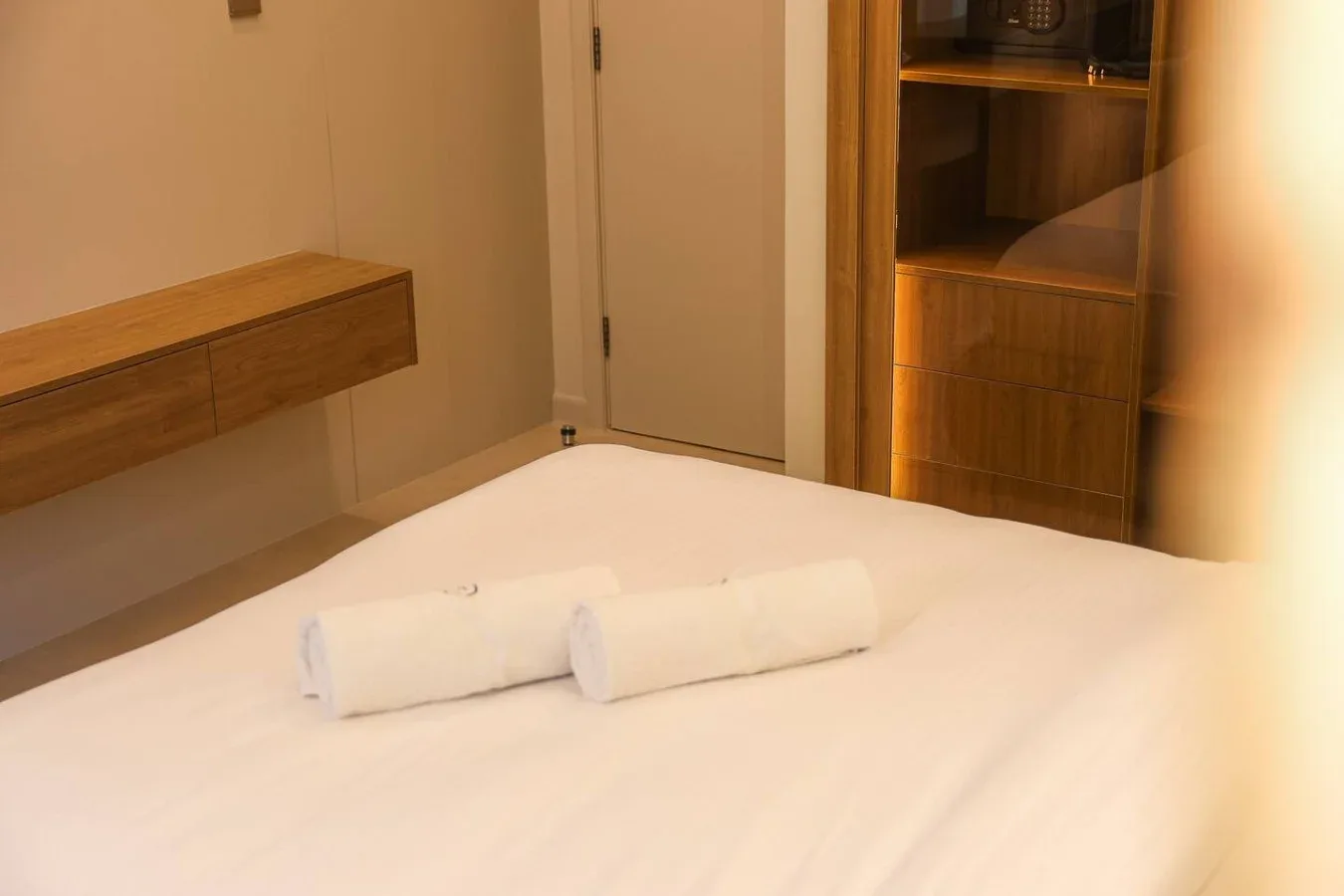 Dormitorio con una cama y dos toallas enrolladas.