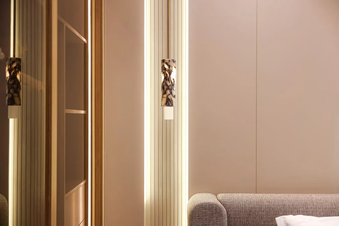 Una habitación con luz tenue tiene un sofá junto a un espejo estrecho.