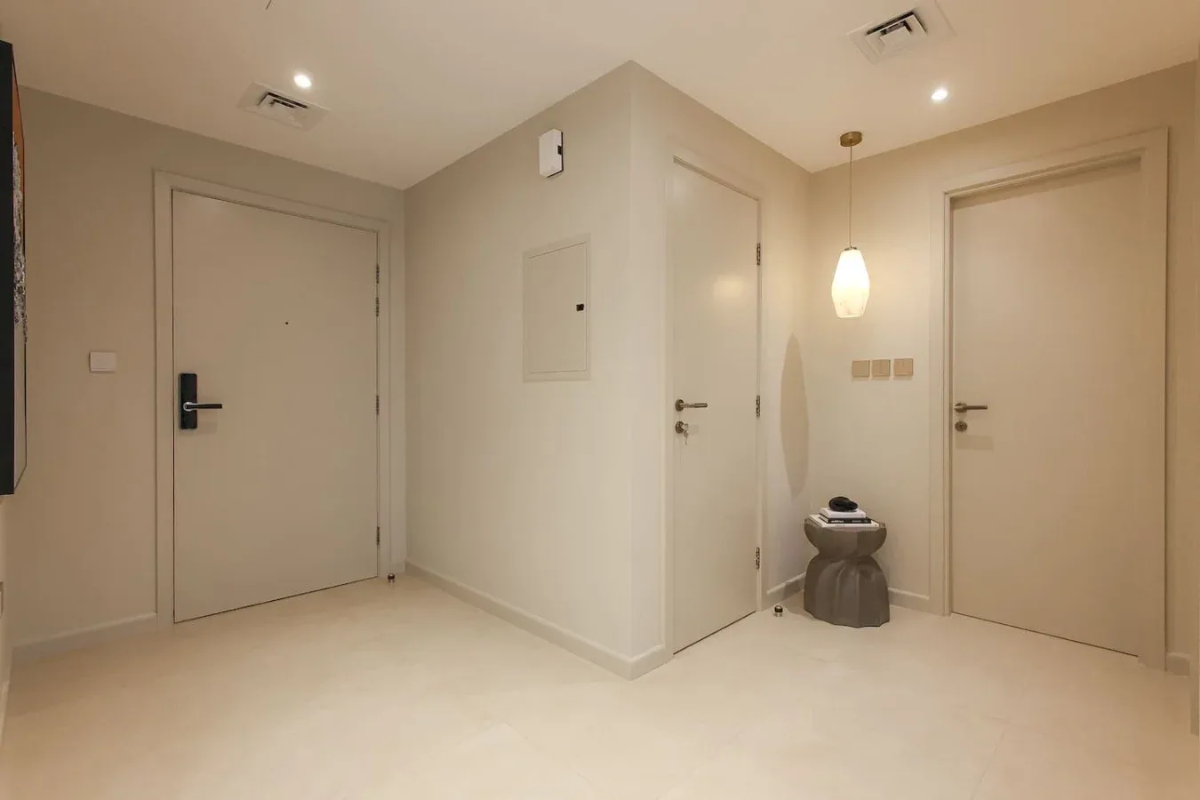 Un pasillo interior luminoso con varias puertas cerradas y una lámpara colgante.