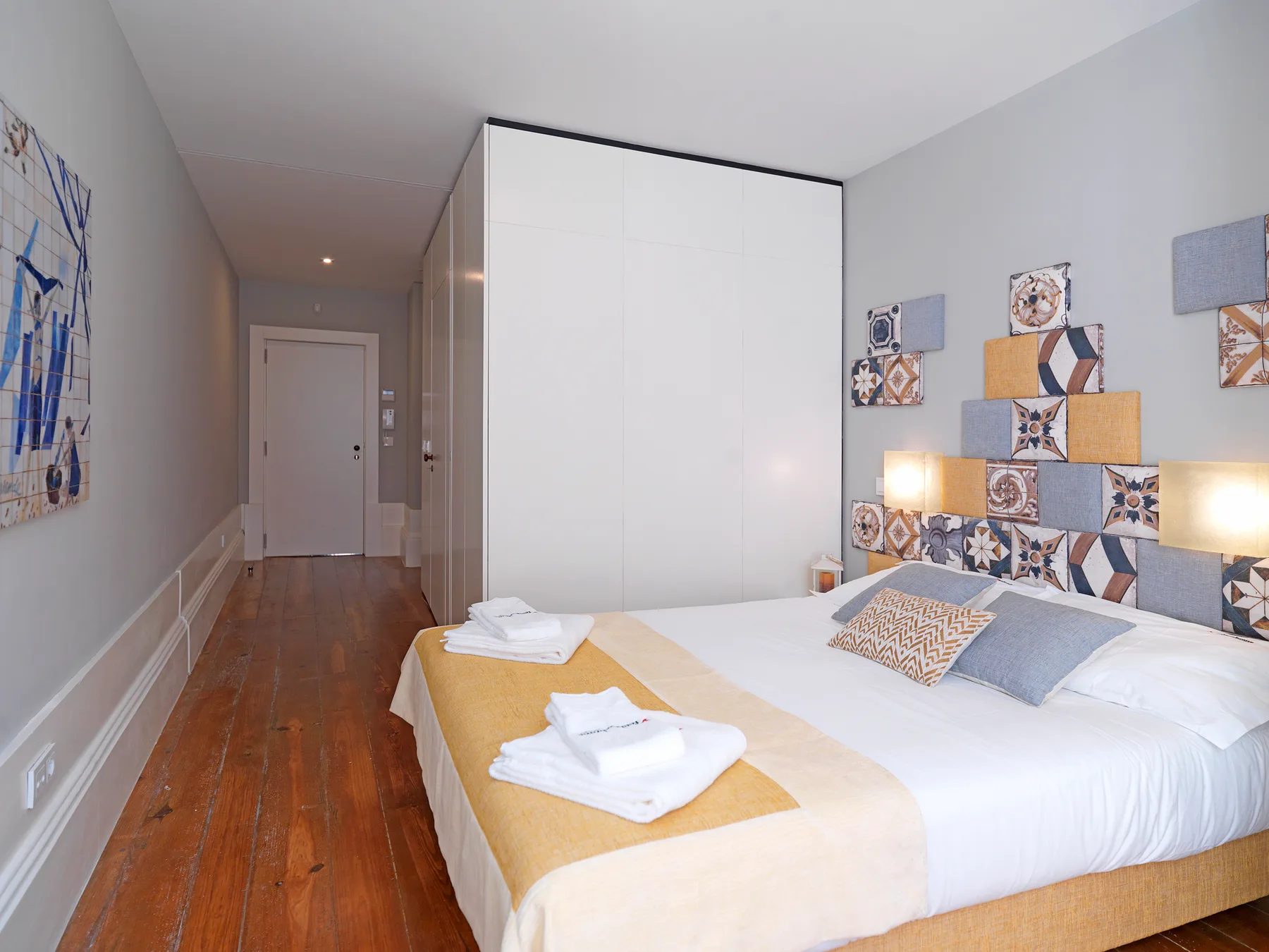 A bedroom with a neatly made bed and colorful patterned wall panels.