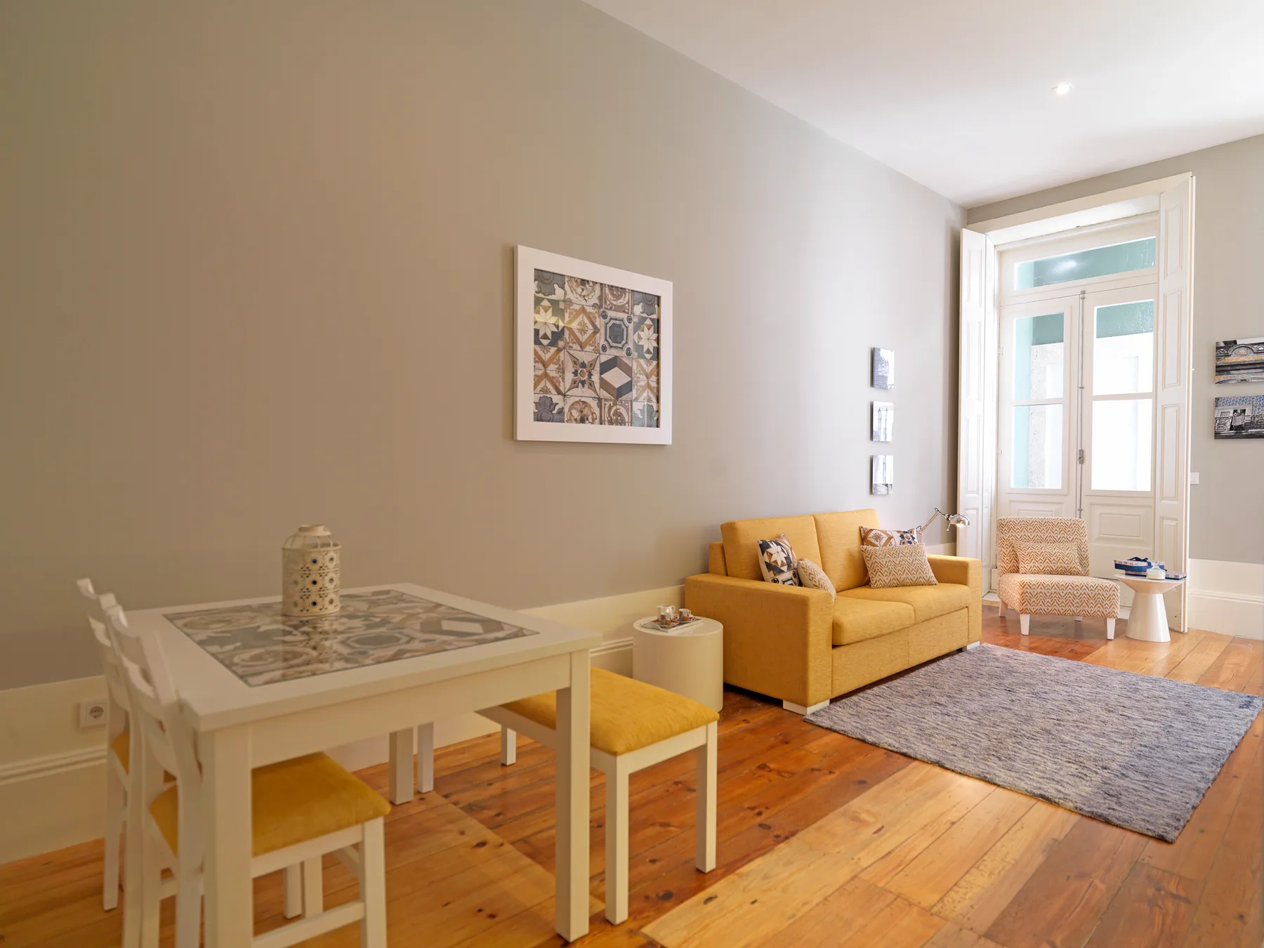 A bright living room with a dining table, seating, and a rug.