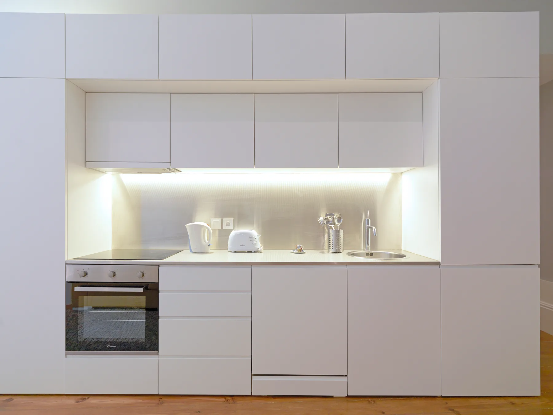 A modern kitchen with white cabinets, a countertop, and an oven.