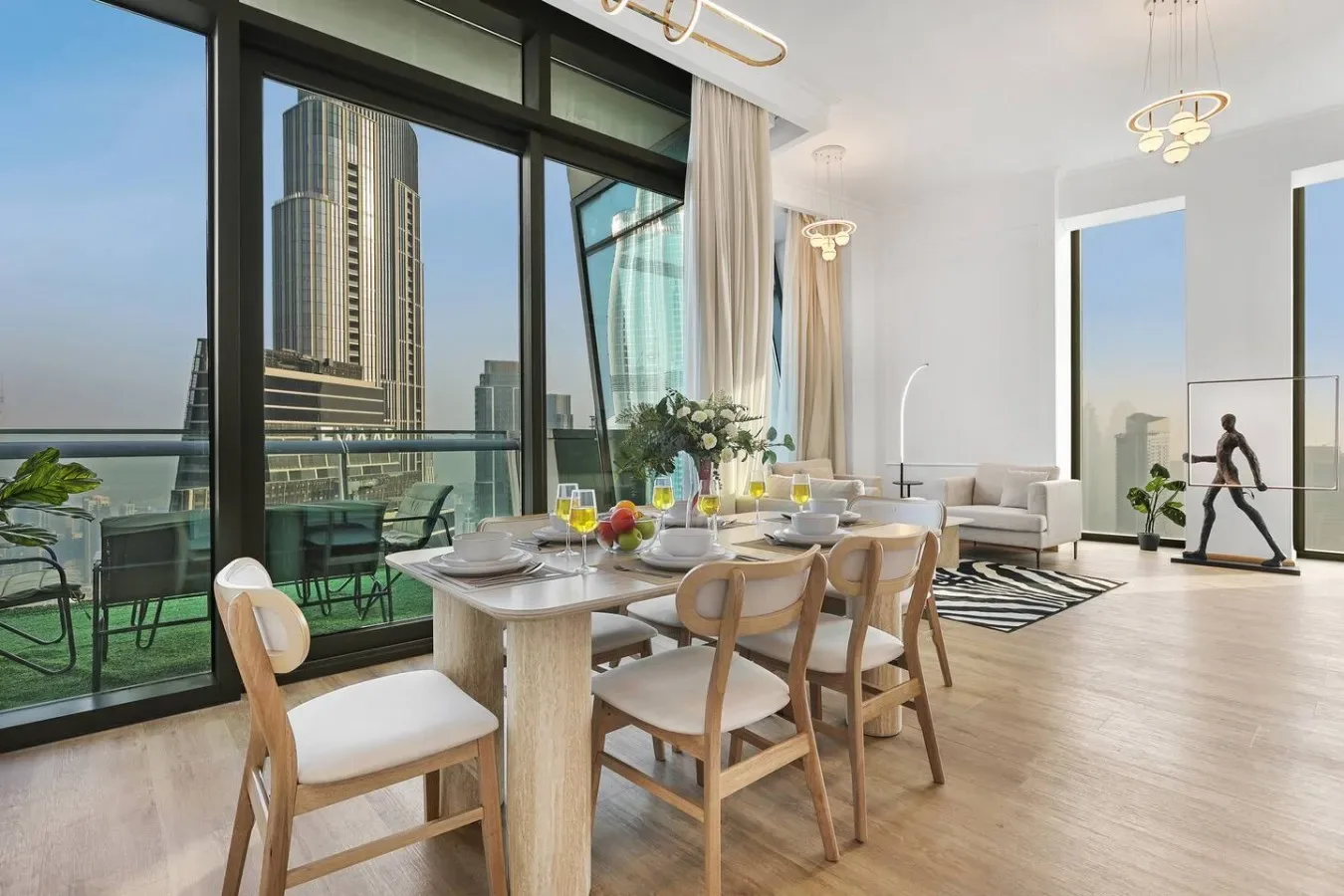 Un comedor luminoso con la mesa puesta junto a ventanas de piso a techo.