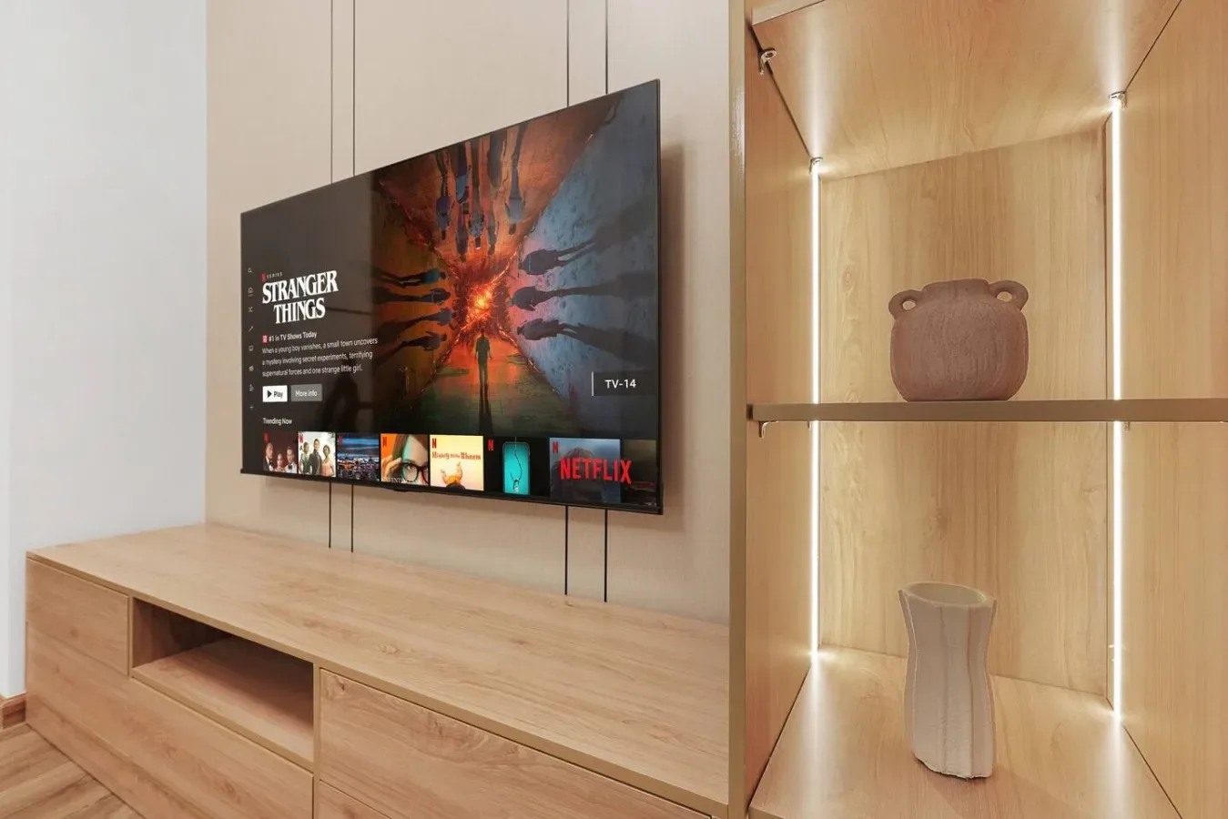 Un televisor sobre un mueble de madera está junto a estantes iluminados.