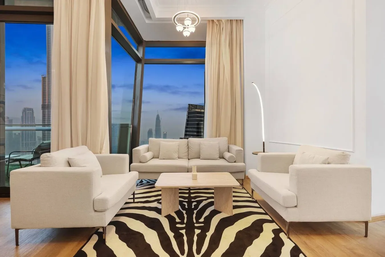 Una sala luminosa con asientos alrededor de una mesa de centro y grandes ventanas.