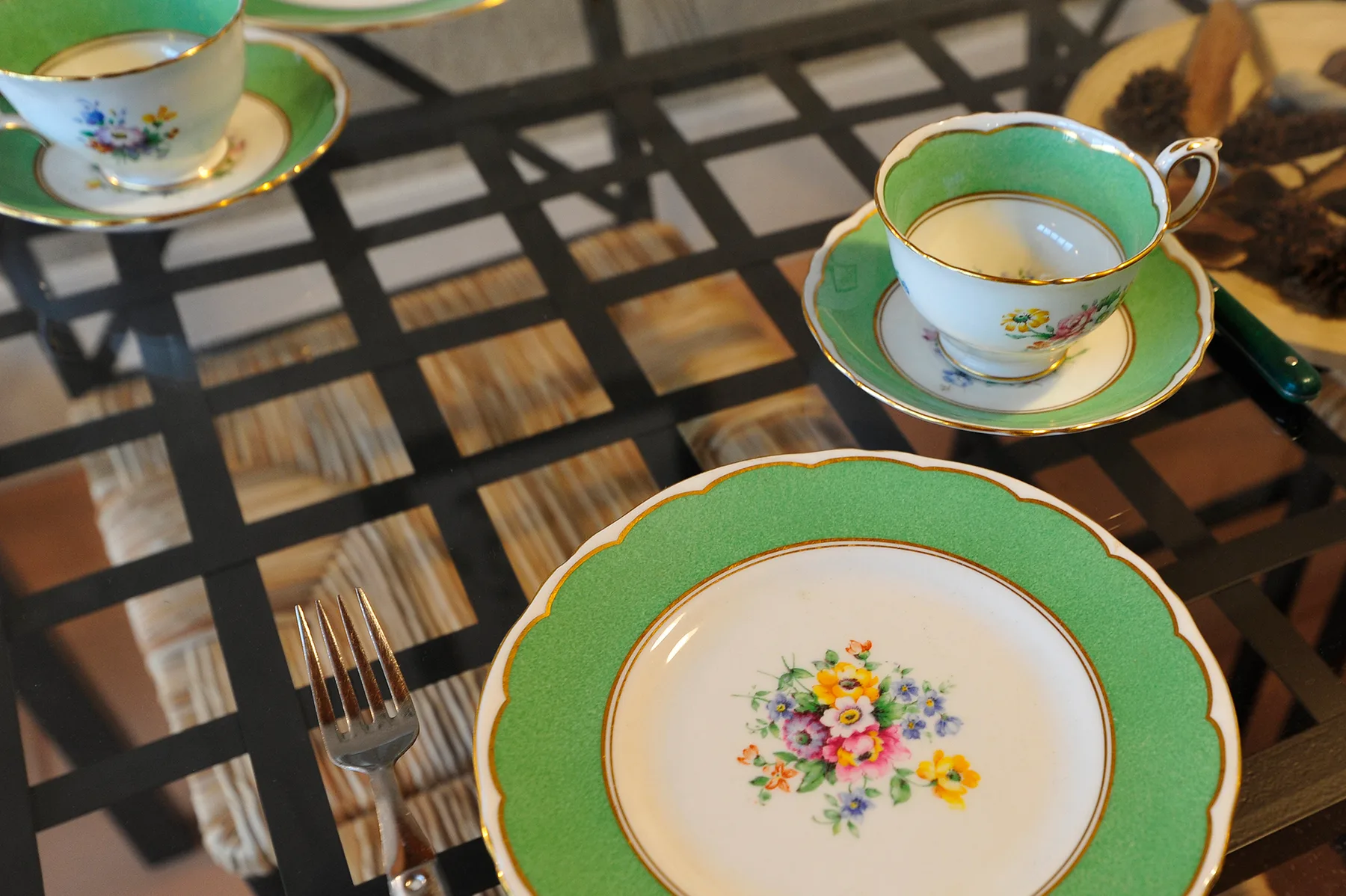 Una mesa de comedor muestra vajilla floral con bordes verdes y un tenedor.