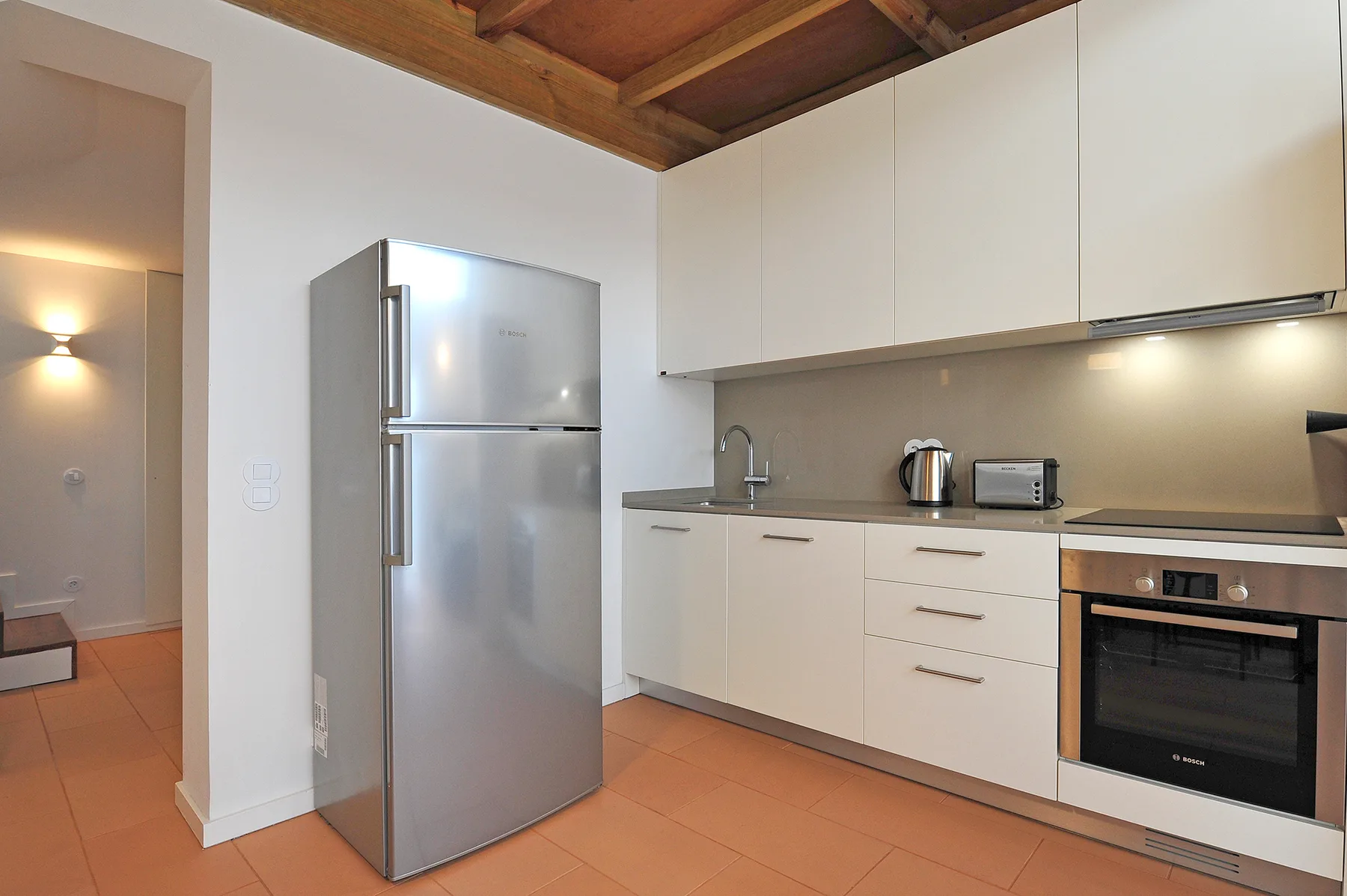 Una cocina con gabinetes blancos, un refrigerador y un horno.