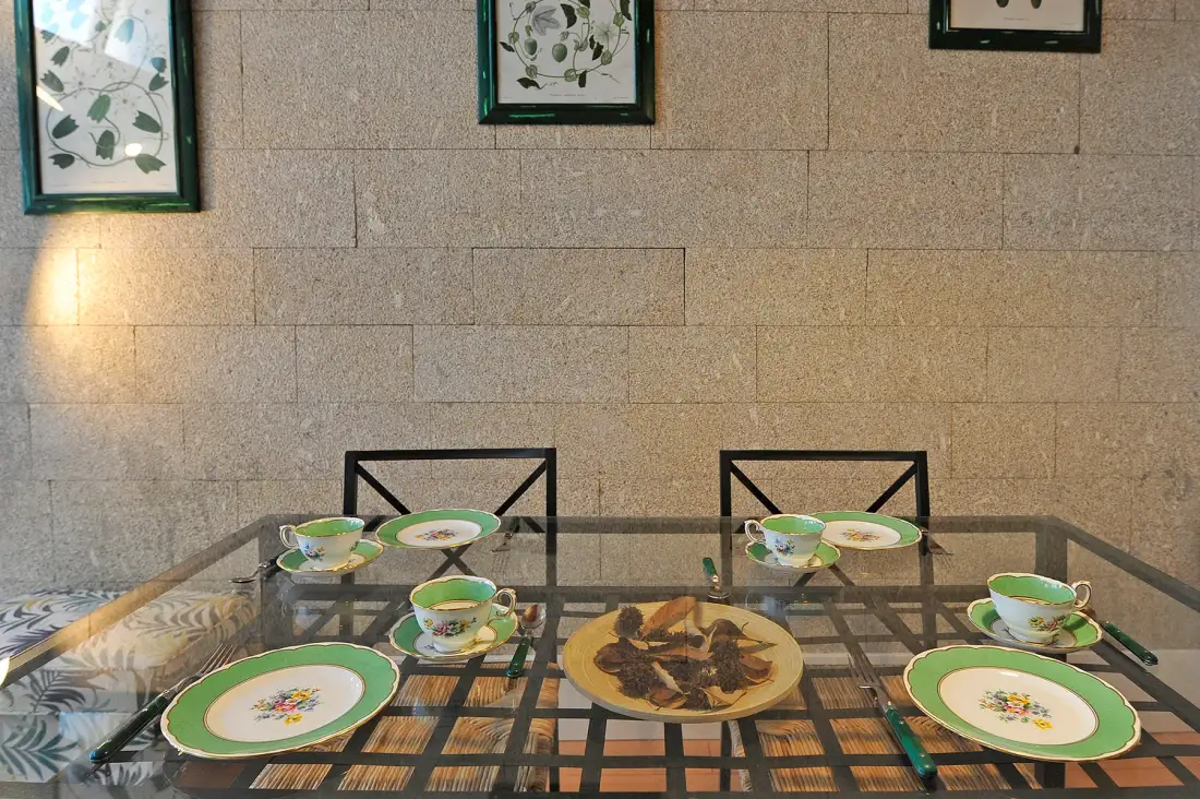 Comedor con la mesa puesta y cuadros botánicos enmarcados en la pared.