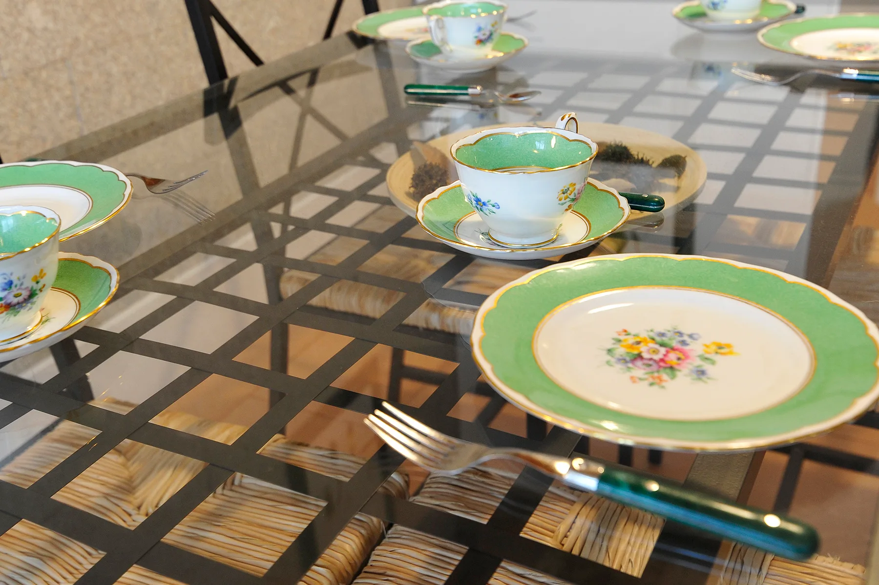 Una mesa de comedor de vidrio está puesta con platos, tazas y cubiertos de colores.