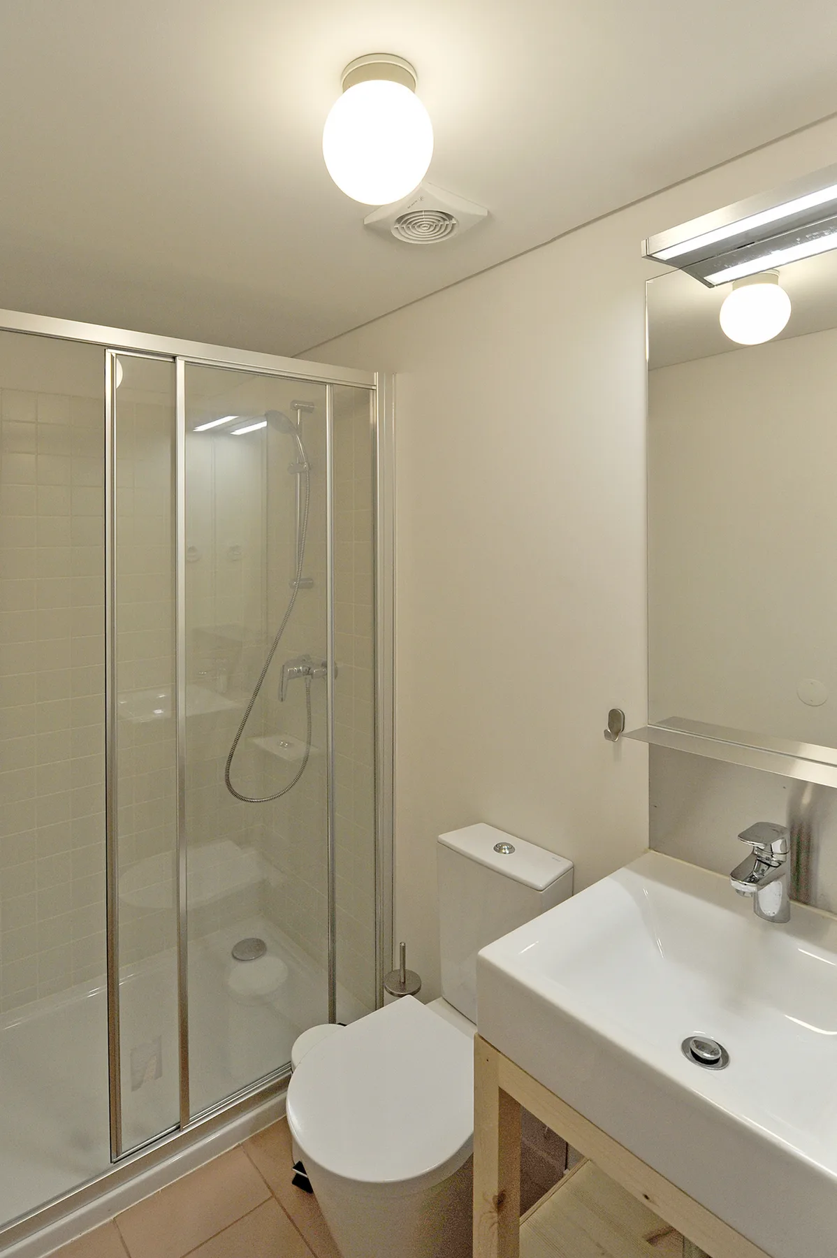 Un baño con ducha de vidrio, inodoro y lavabo.
