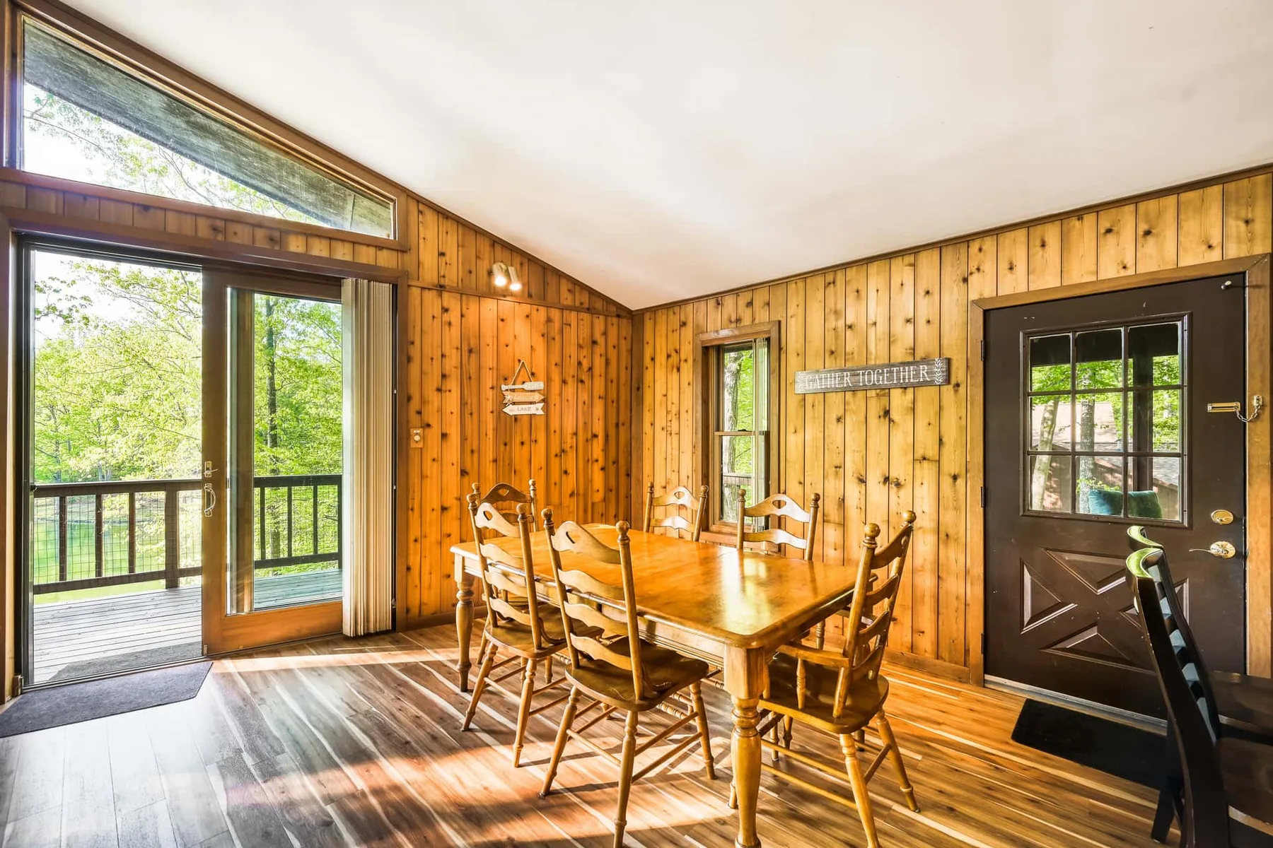 Comedor con paredes de madera, una mesa y sillas junto a puertas de vidrio.