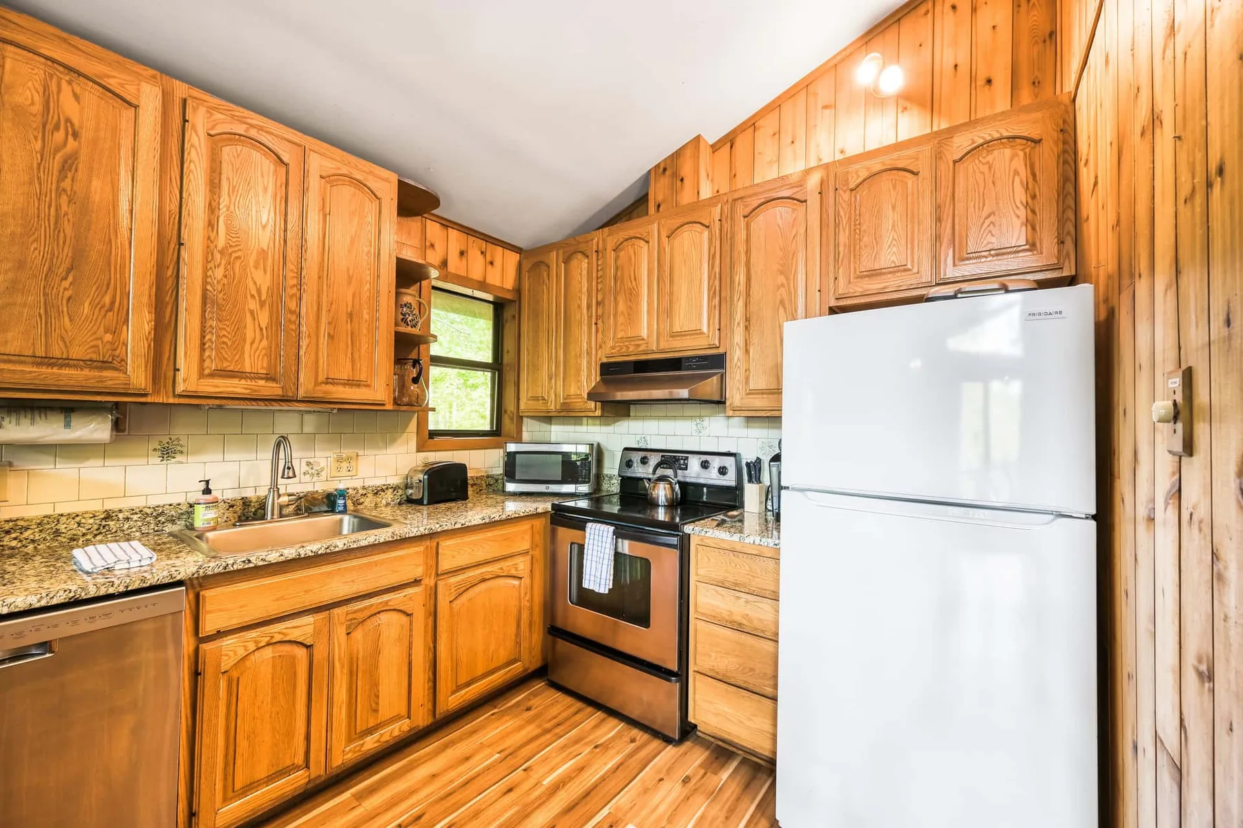 Una cocina revestida de madera con gabinetes, una estufa y un refrigerador.