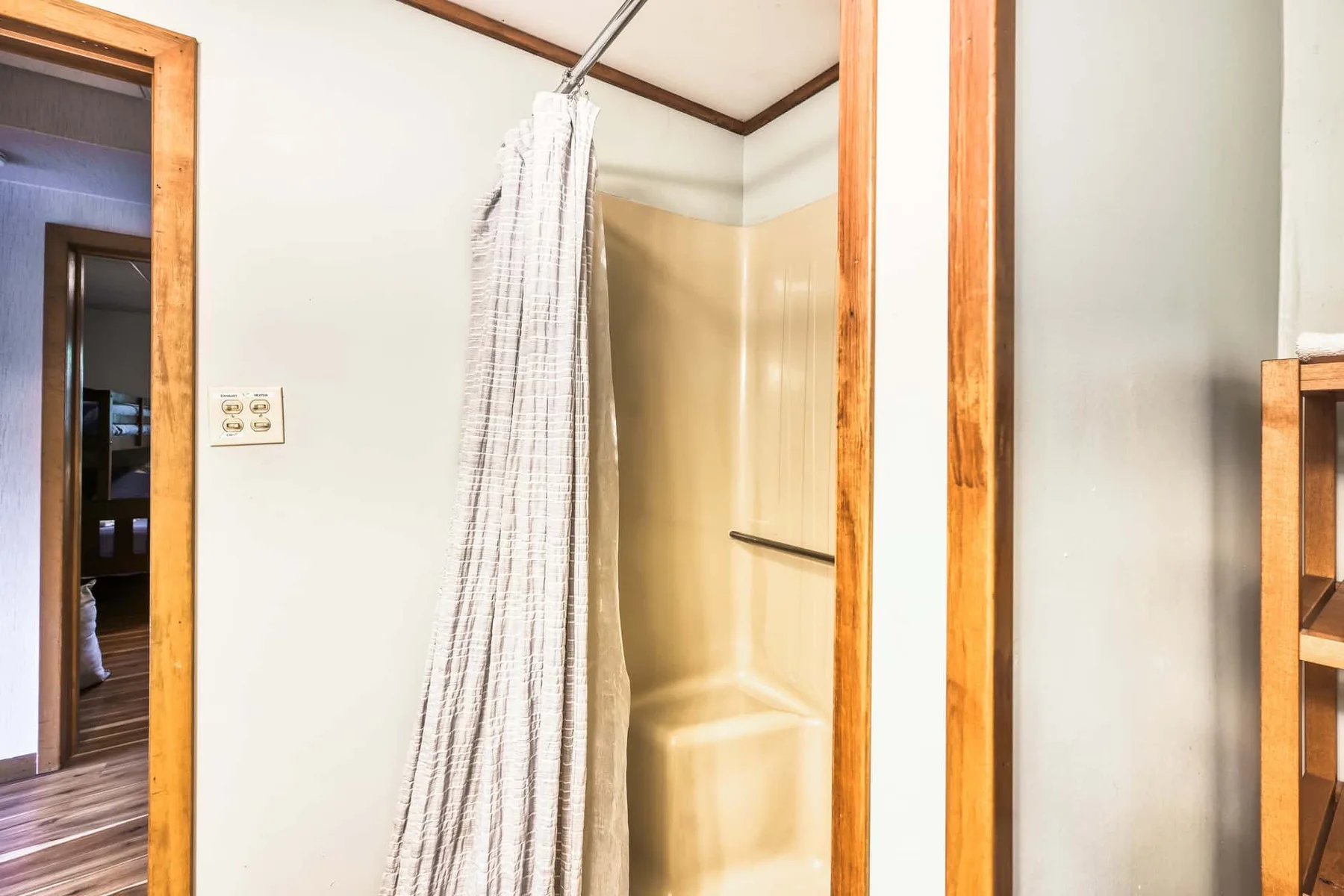Zona de ducha de un baño con cortina y barra de apoyo en la pared.