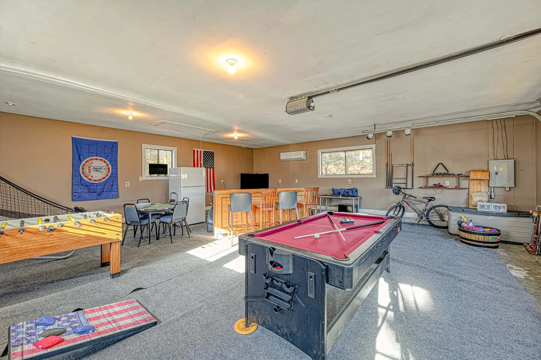 A recreation room with a pool table, foosball table, and seating.