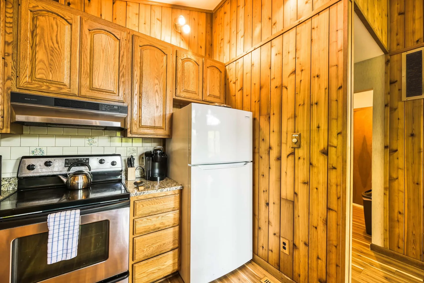Una cocina revestida de madera con estufa, refrigerador y gabinetes de madera.