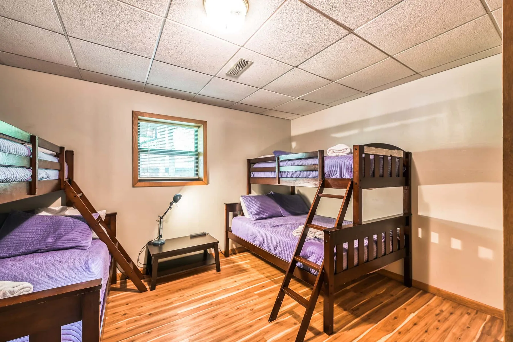 Un dormitorio con literas, una ventana y suelo de madera.