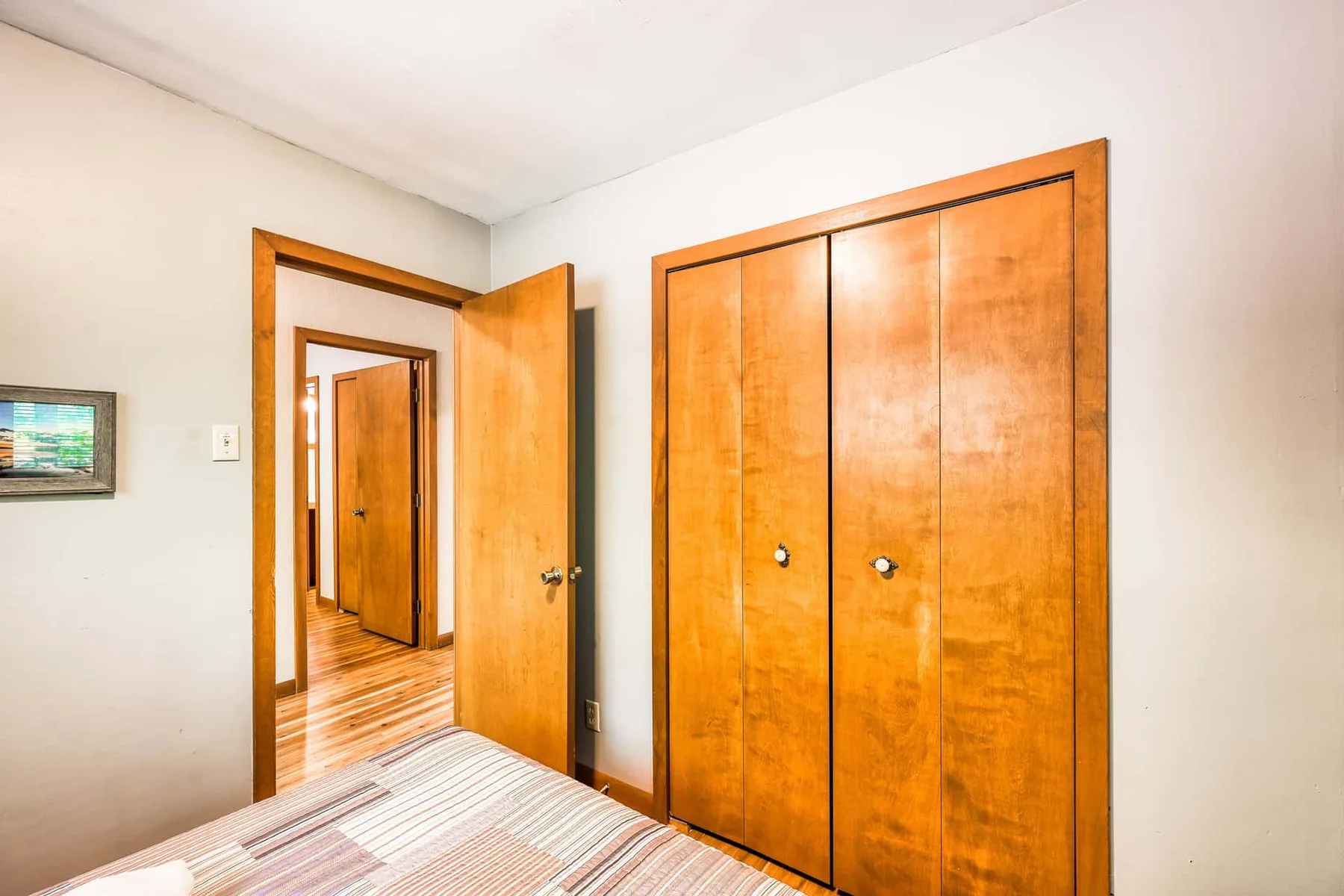 Un dormitorio con armarios de madera y una puerta abierta hacia un pasillo.