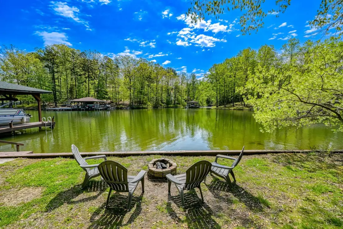 Una zona de asientos junto al lago da a aguas tranquilas y una orilla arbolada.