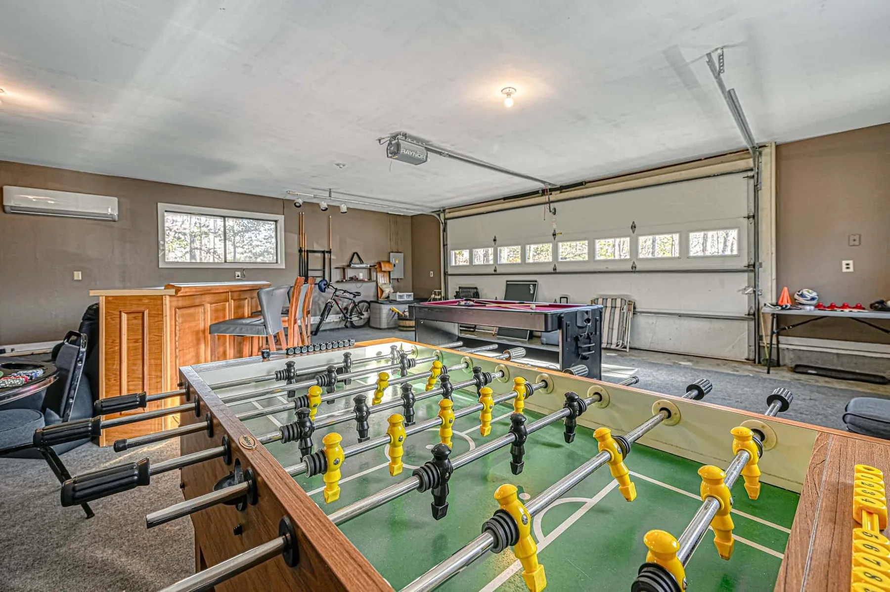 Una sala de juegos con mesas de futbolín y una mesa de billar.