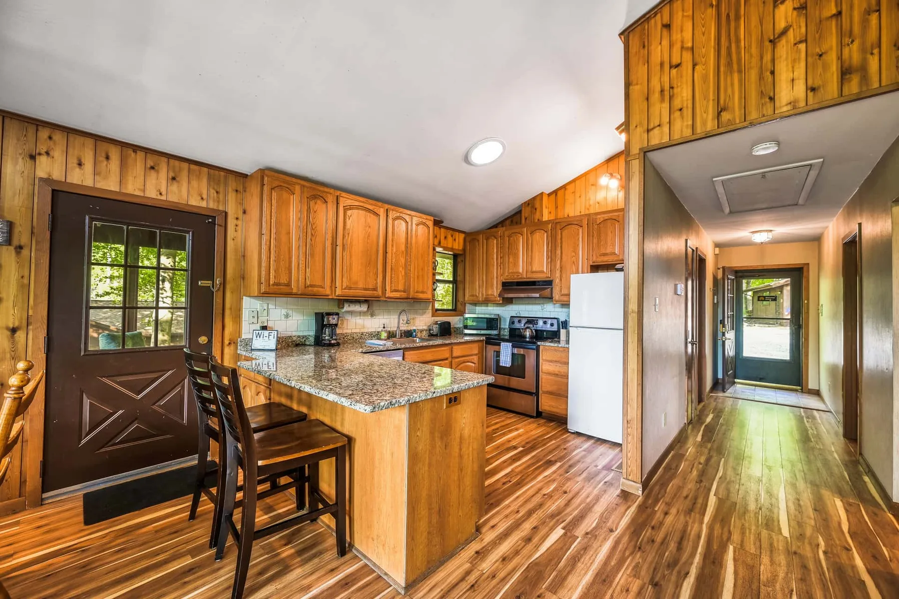 Una cocina revestida de madera con una isla central y un pasillo al lado.