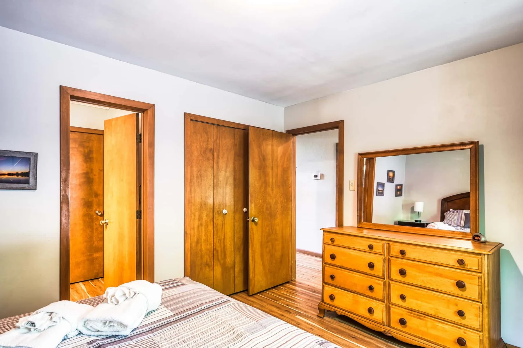 Un dormitorio con armarios de madera, una cómoda y una cama en primer plano.