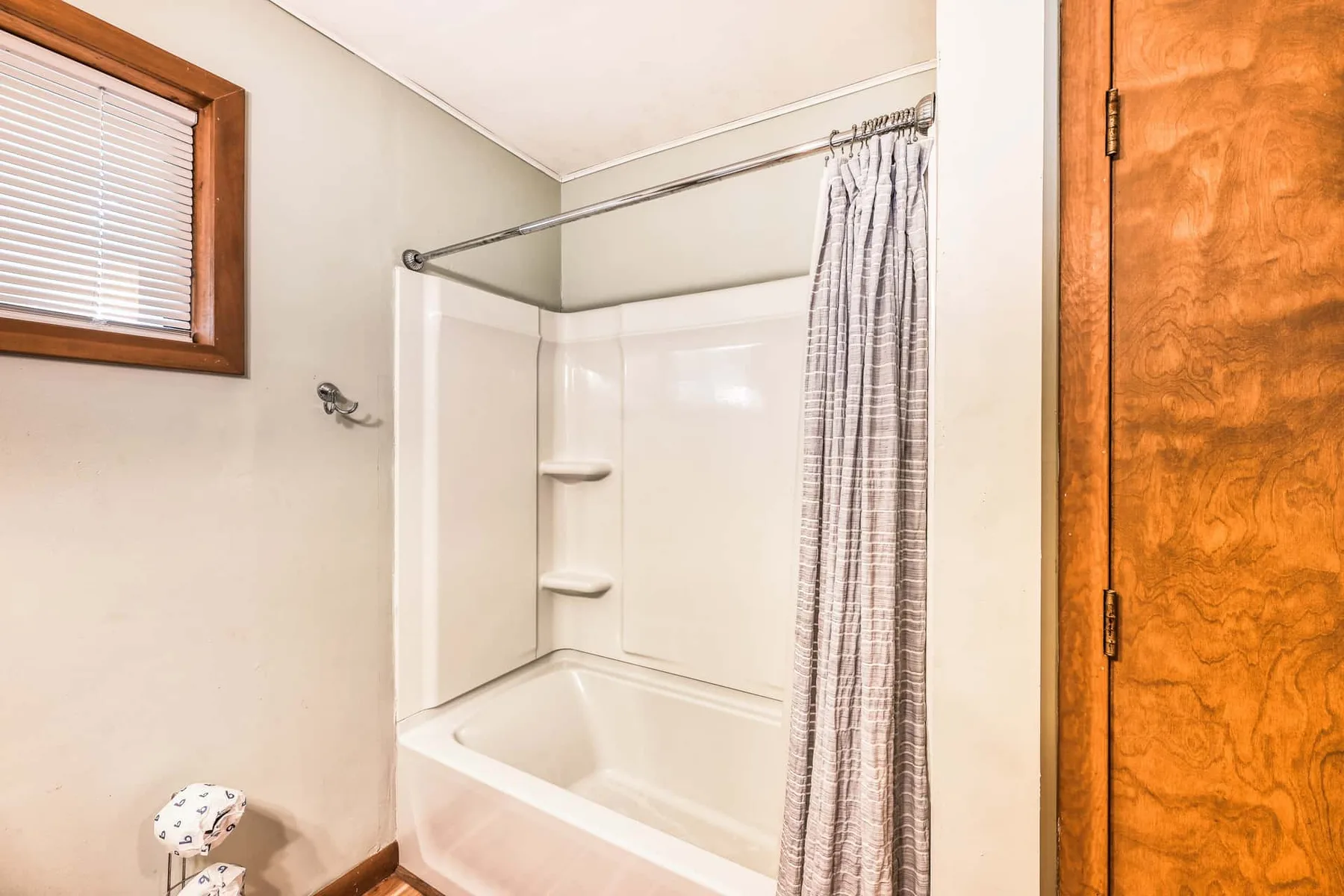 Un baño con bañera y cortina de ducha junto a una puerta de madera.