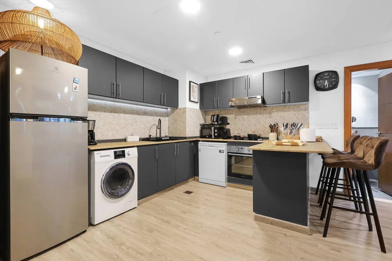 Una cocina moderna con gabinetes oscuros, electrodomésticos de acero inoxidable y una isla central.
