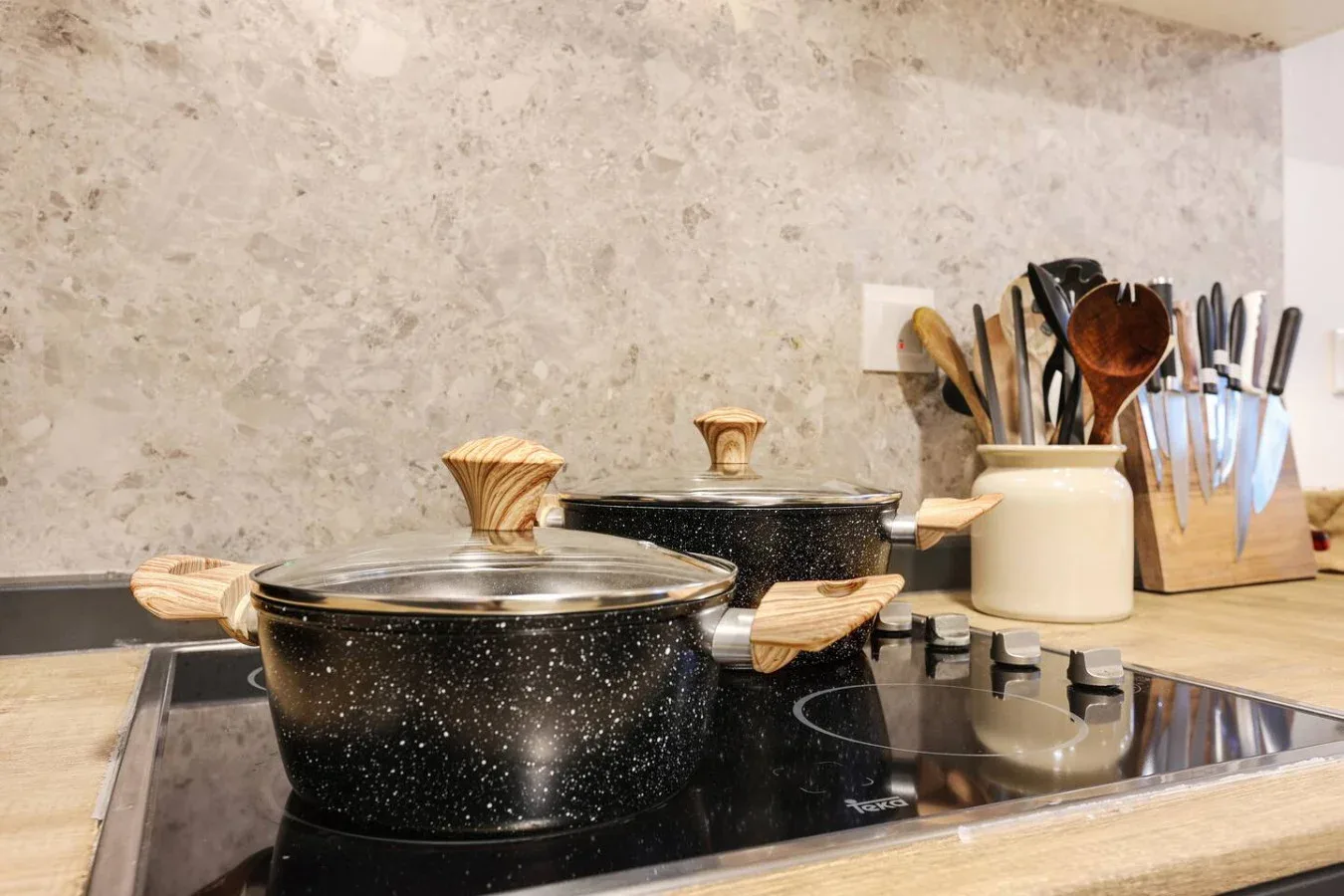 Una estufa de cocina con una olla moteada y utensilios de cocina cerca.