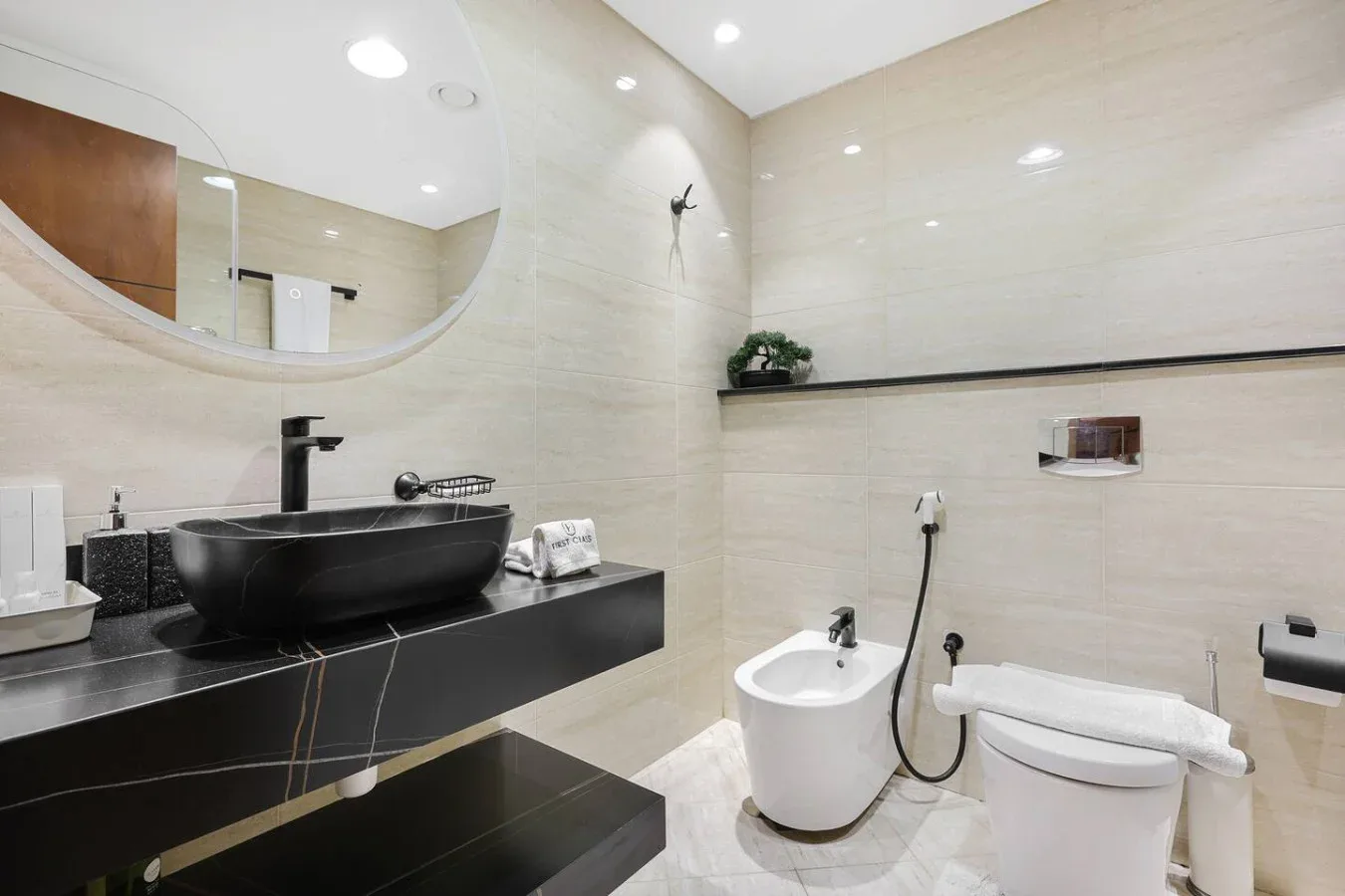 Un baño moderno con mueble oscuro, lavabo sobre encimera, bañera e inodoro.