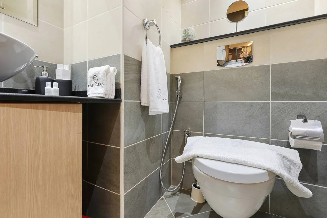 Un baño alicatado con inodoro, lavabo y toallas blancas.