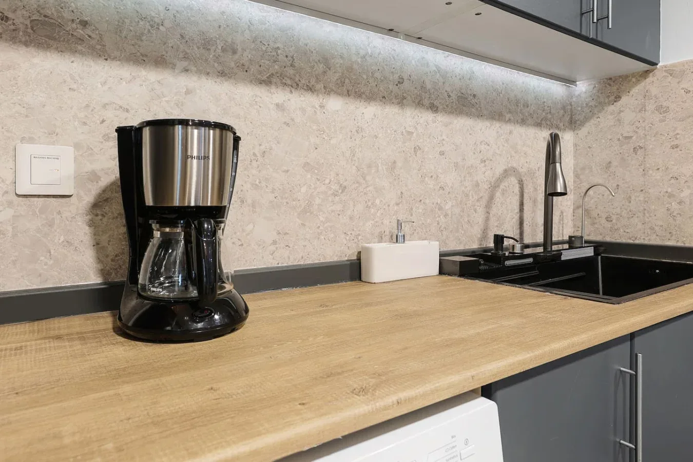 Una encimera de cocina con una cafetera junto al fregadero.