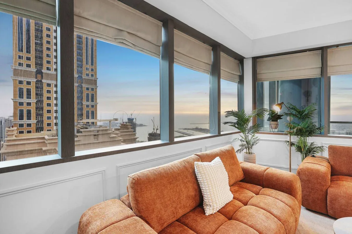 Una sala luminosa con asientos naranjas y grandes ventanas con vistas a la ciudad.