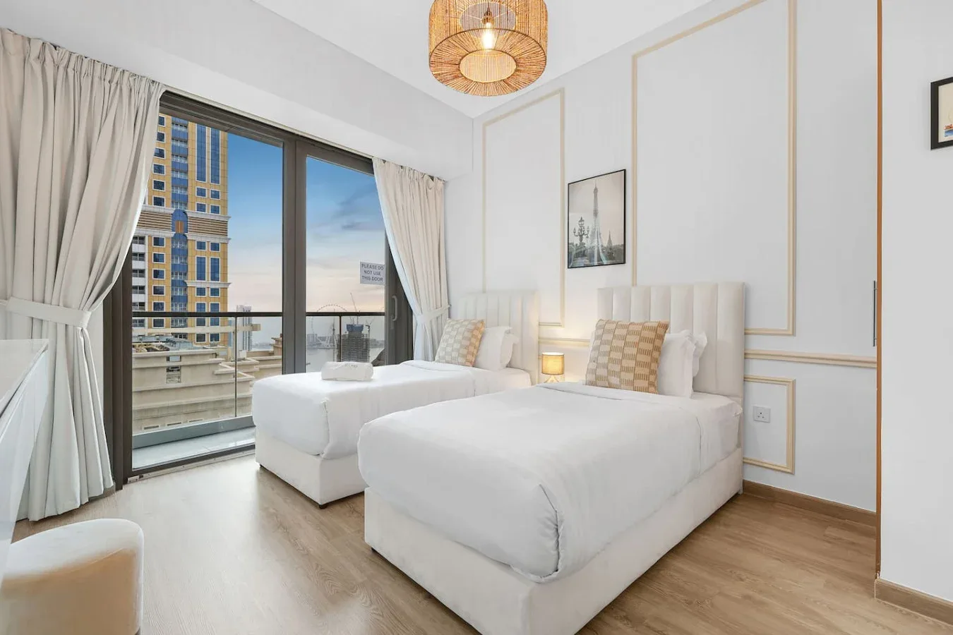 Un dormitorio luminoso con dos camas junto a grandes ventanas.