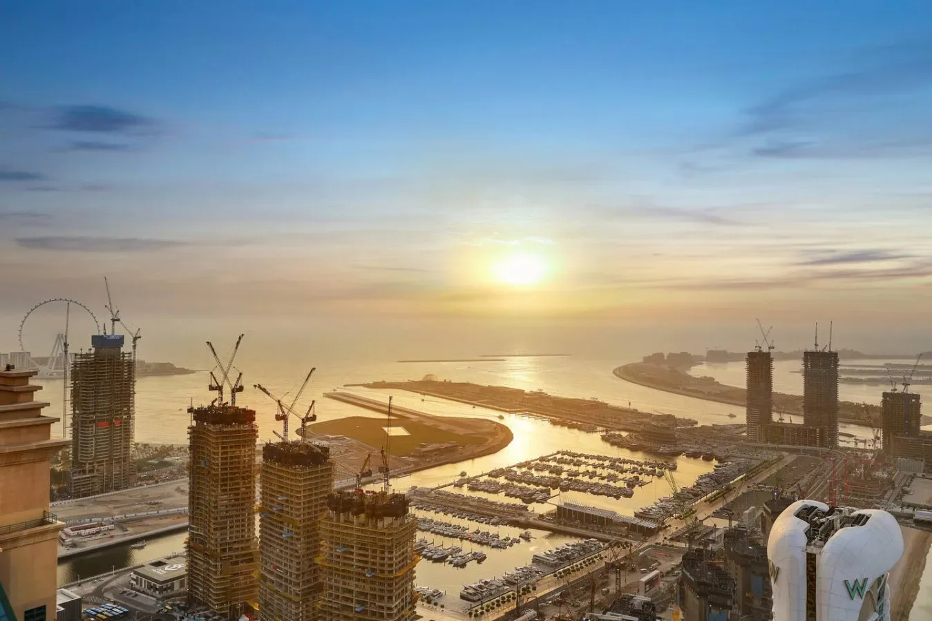 Una zona costera en construcción y una marina dan al agua al atardecer.