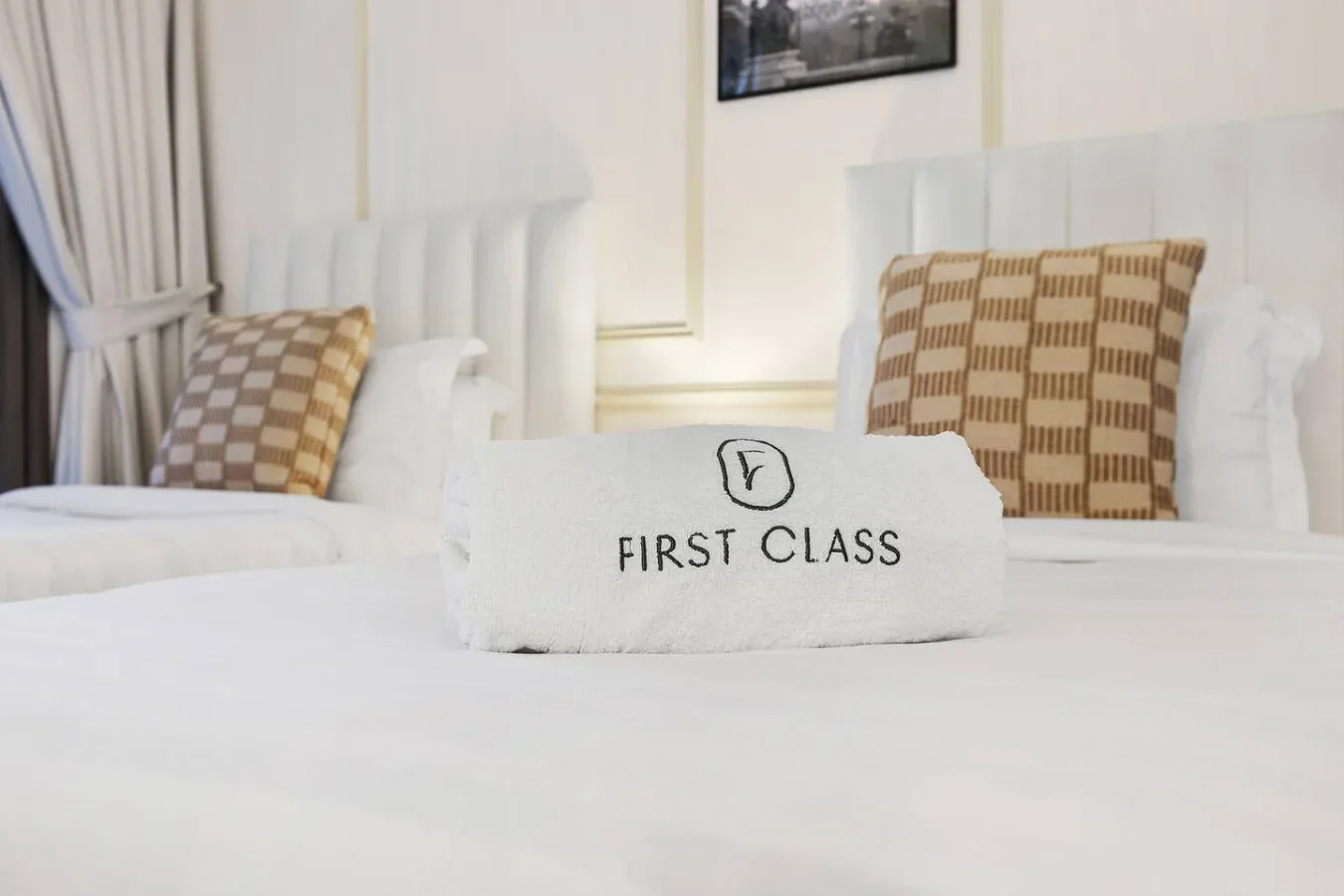 Un dormitorio con ropa de cama blanca y almohadas estampadas sobre las camas.