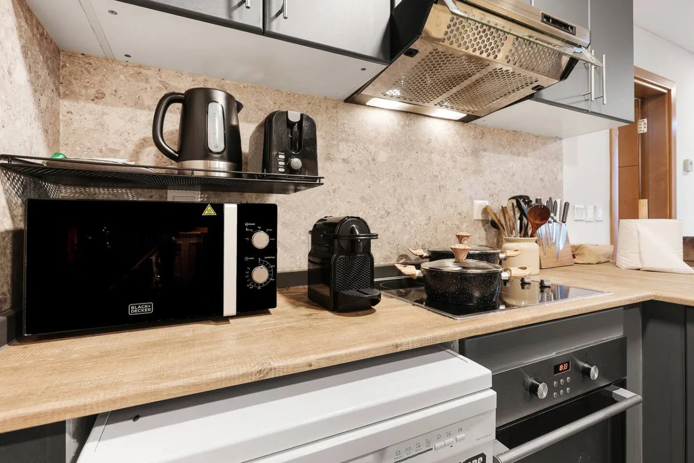 Una encimera de cocina con pequeños electrodomésticos, utensilios de cocina y un horno integrado.