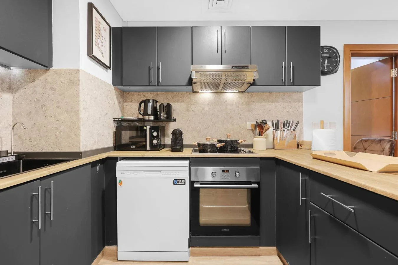 Una cocina moderna con gabinetes oscuros, encimeras claras y electrodomésticos integrados.