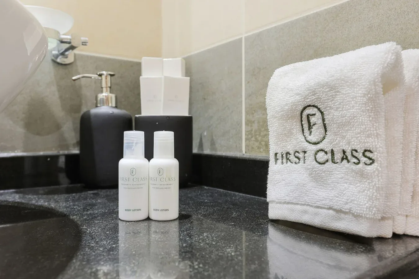 Un tocador de baño muestra artículos de aseo junto a una toalla blanca doblada.