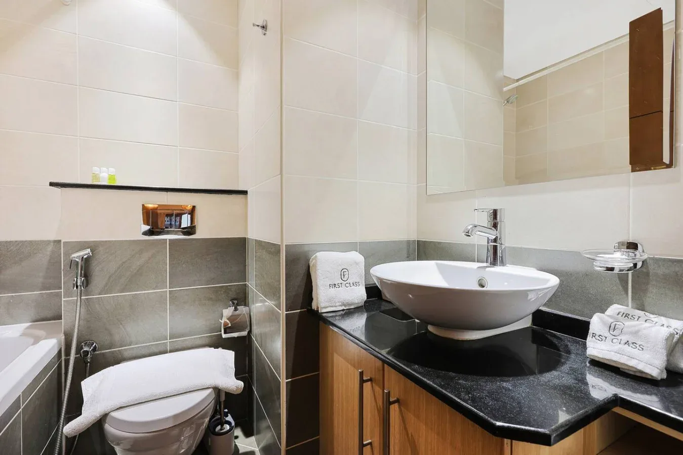Un baño alicatado con un inodoro y un lavabo sobre una encimera oscura.