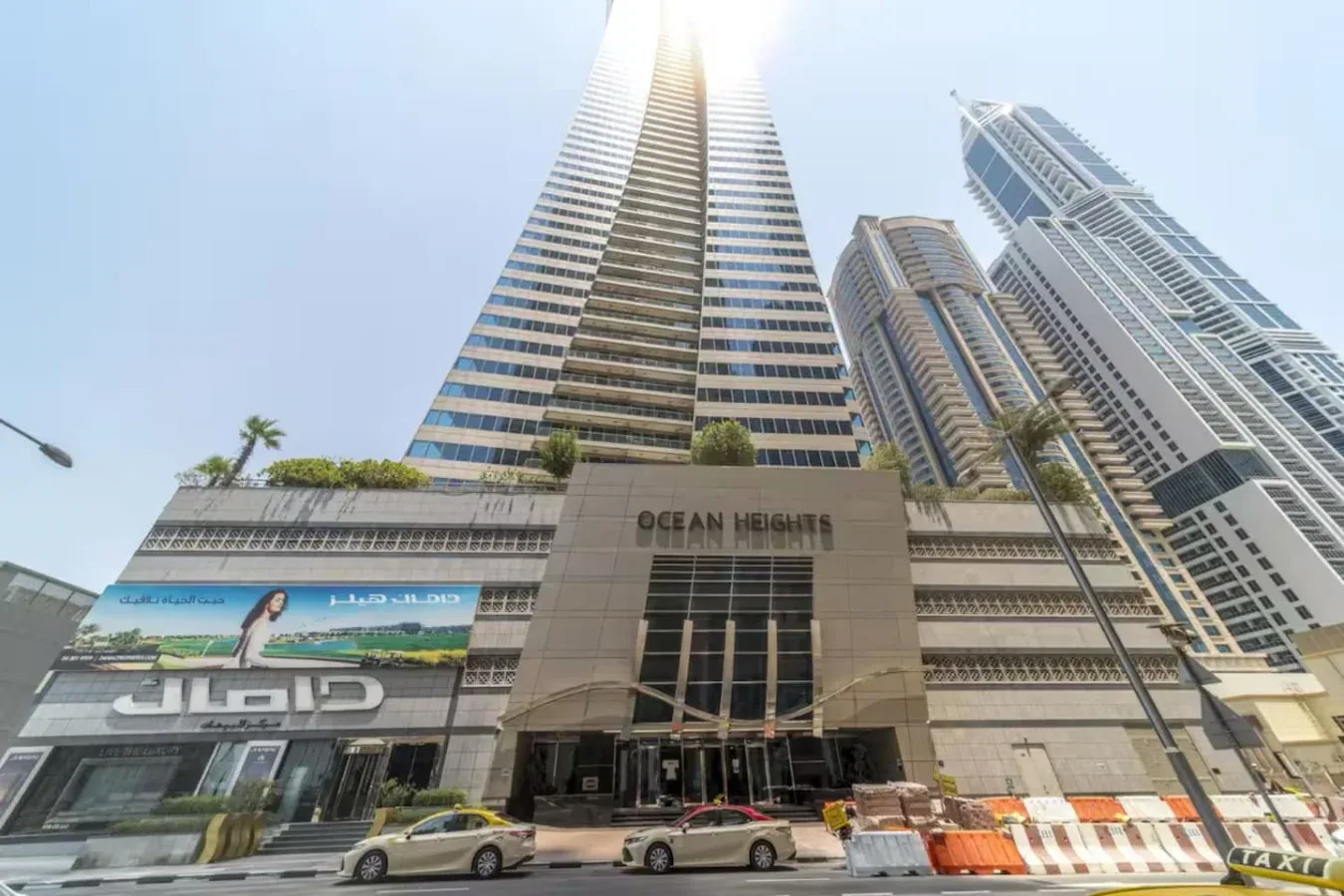 Un edificio alto y moderno se eleva sobre locales comerciales y la calle.