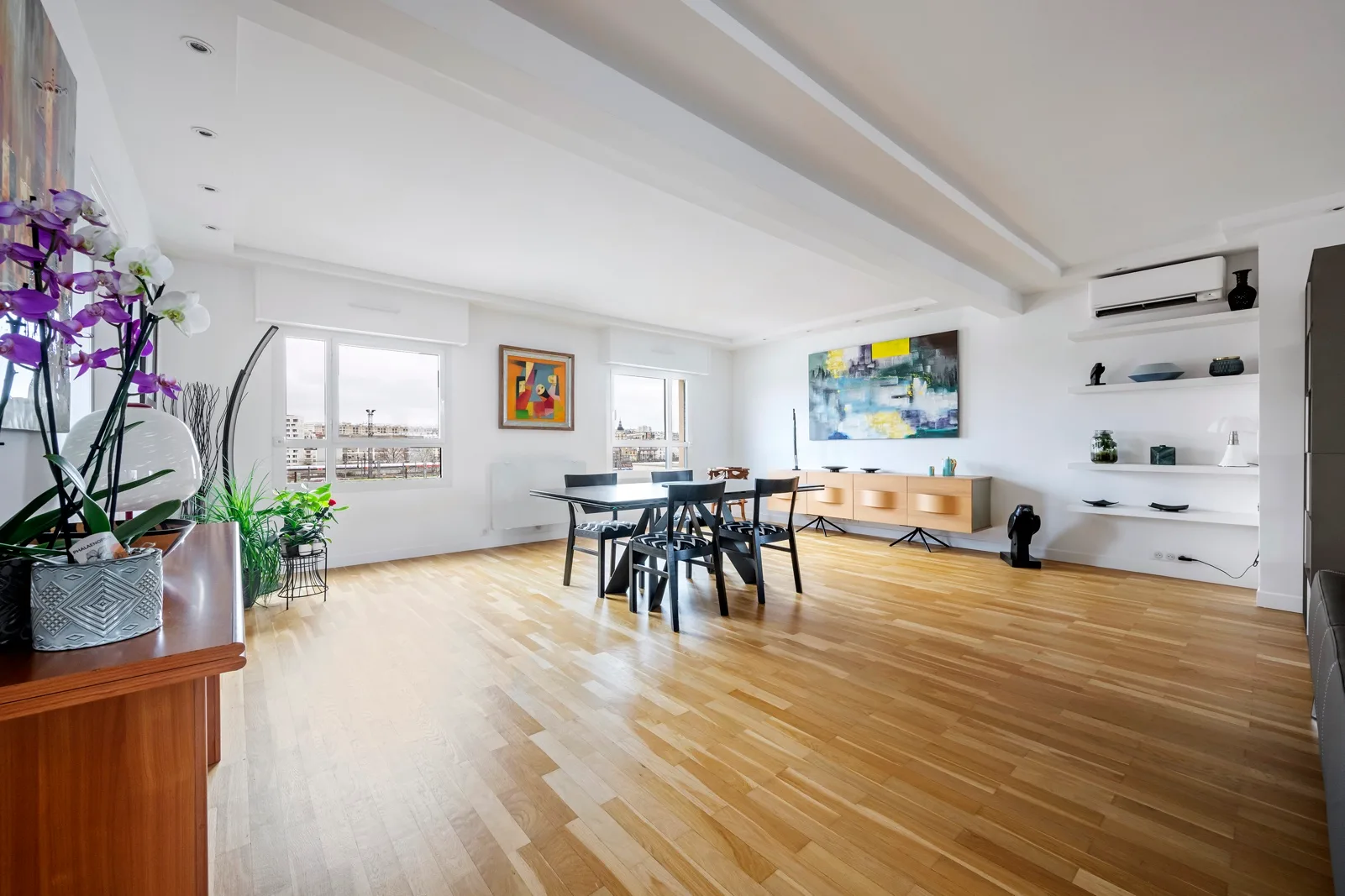 A bright open dining and living area with a table, seating, and large windows.