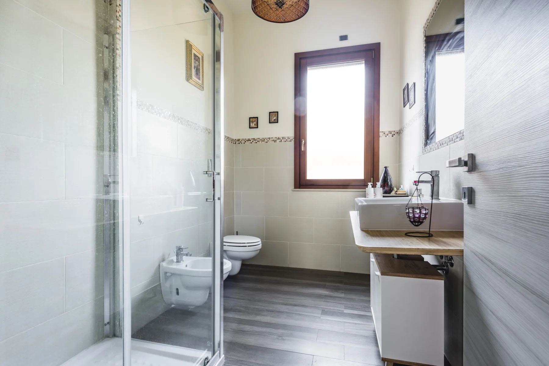 Un baño luminoso con ducha de vidrio, inodoro y lavabo.